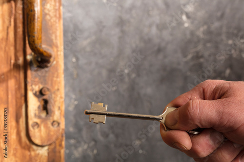 Hand with vintage key and keyhole close up view