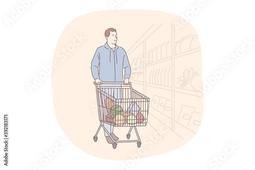 Shopping, supermarket, grocery store concept. Young positive man cartoon character walking along shelves in supermarket with trolley cart with fresh products inside and choosing food ingredients 