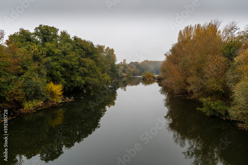 Landscape with the   rbigo River and riverside vegetation in autumn with the gray sky. Province of Le  n  Spain.