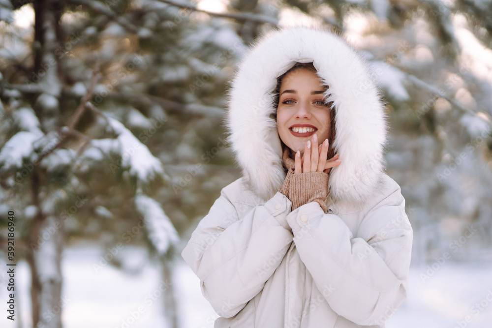 Portrait of young beautiful woman in a snowy park. Cheerful lady in winter clothes posing with joy outside in the snow forest. Winter holiday, Christmas, New year. Portrait of young beautiful woman in a snowy park. Cheerful lady in winter clothes posing with joy outside in the snow forest. Winter holiday, Christmas, New year.