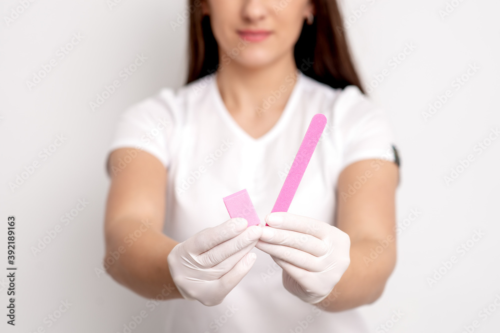Manicure tools in hands of young female manicure master on white background. Selective focus Manicure tools in hands of young female manicure master on white background. Selective focus