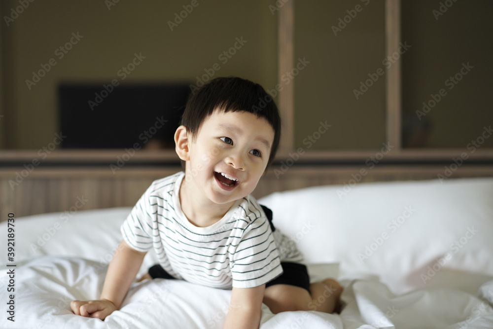 2 years old little boy dressed in Striped Tshirt are relaxing and playing in the parent's bed, warm and cozy scene. Portrait Lively kid with smiling face is playing in bed, selective focus. 2 years old little boy dressed in Striped Tshirt are relaxing and playing in the parent's bed, warm and cozy scene. Portrait Lively kid with smiling face is playing in bed, selective focus.