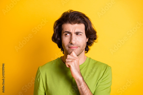 Photo of ponderous smart guy finger chin look side empty space wear green t-shirt isolated yellow color background
