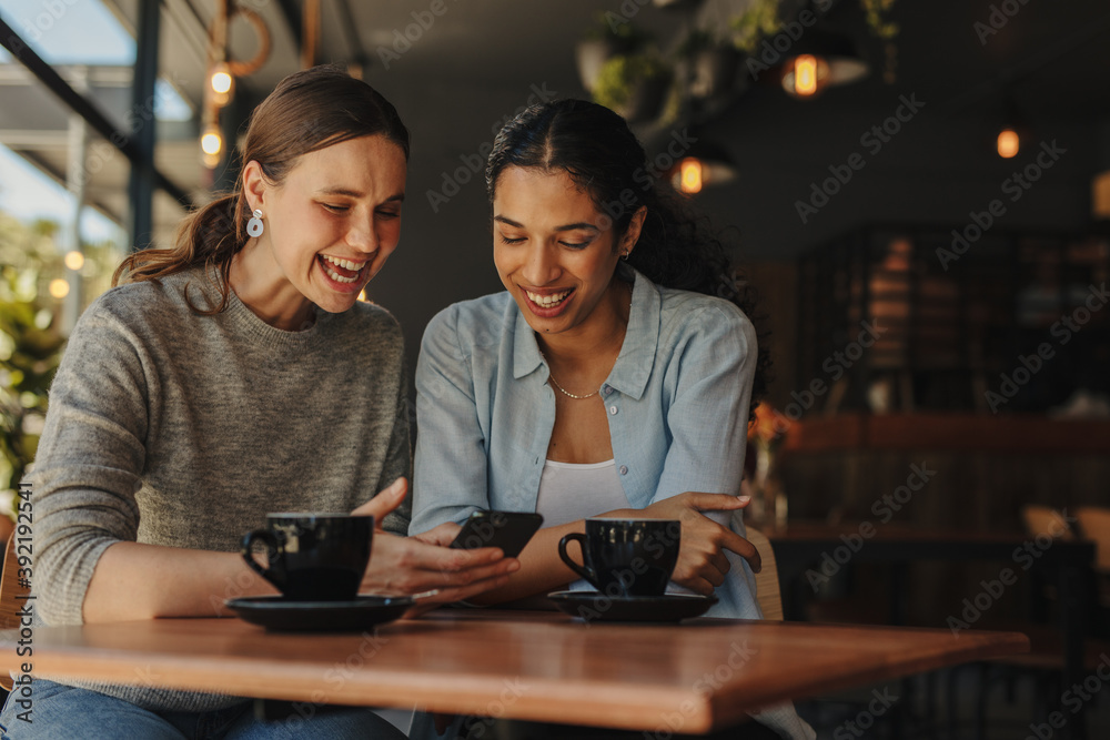 Friends in cafe using phone