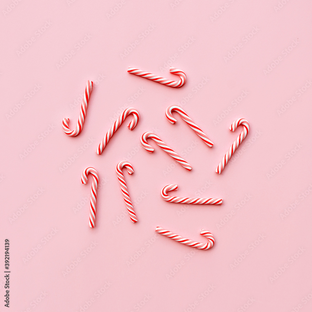 Top view of Christmas candy canes on pastel pink background. Holiday festive celebration greeting card with copy space to addng text Top view of Christmas candy canes on pastel pink background. Holiday festive celebration greeting card with copy space to addng text