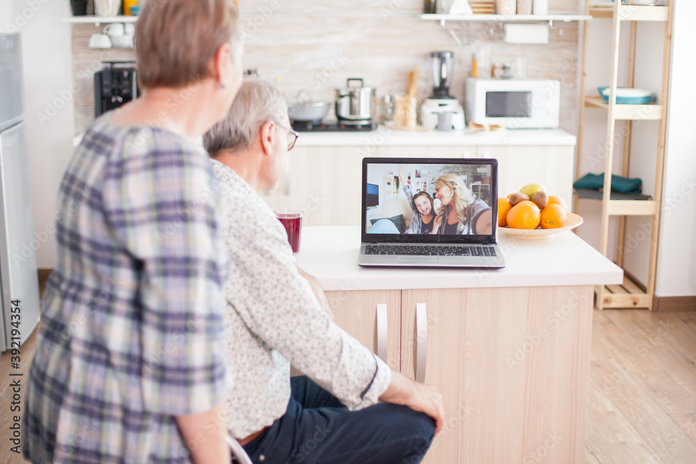 Senior couple talking with niece and daughter on online video call from kitchen. Elderly person using modern communication online internet web techonolgy. Senior couple talking with niece and daughter on online video call from kitchen. Elderly person using modern communication online internet web techonolgy.