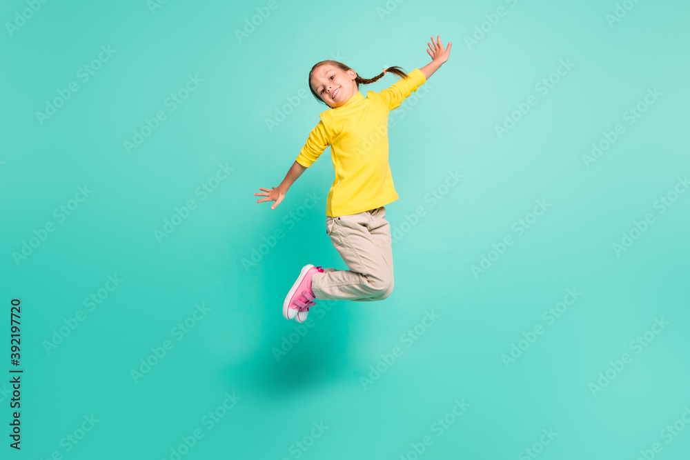 Full size photo of happy girl jump in air wear yellow turtleneck white pants isolated on shine teal color background