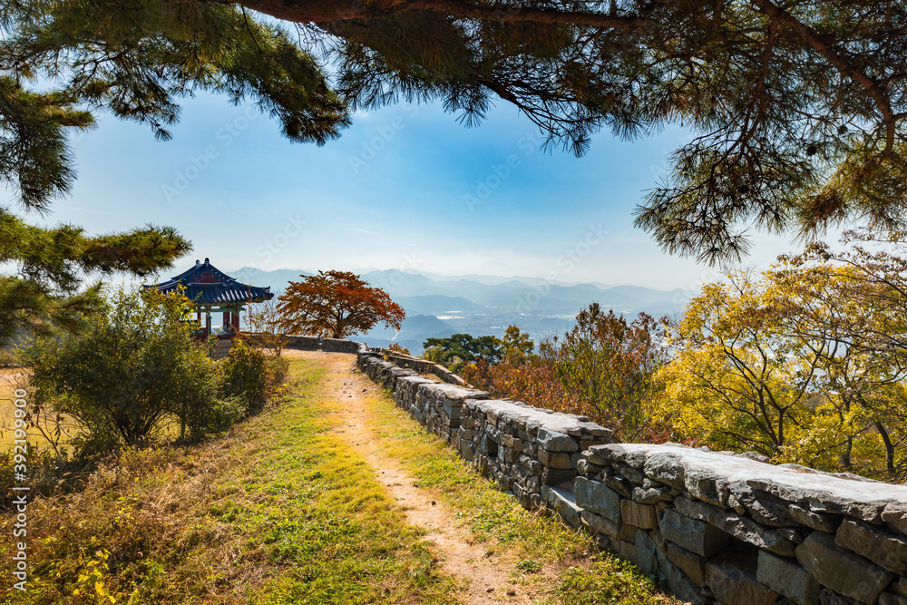 Beautiful Korean autumn scenery. Colorful autumn leaves seen from the top of the mountain and traditional buildings along the castle road. Jeollanam-do, Geumseongsanseong, South Korea.