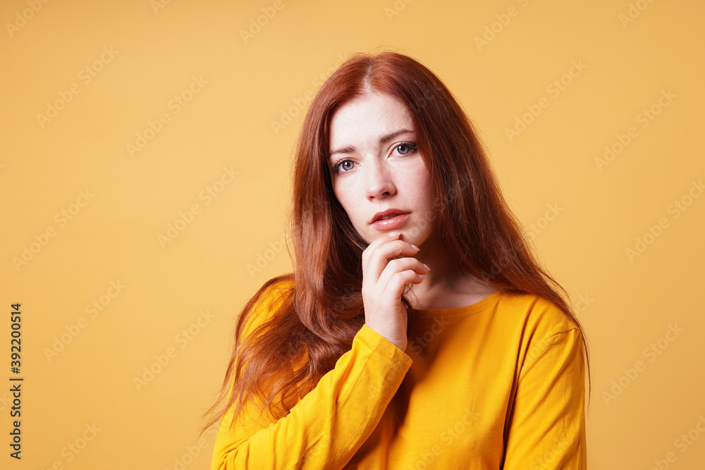 thoughtful young woman with finger on chin gesture - yellow orange color background with copy space thoughtful young woman with finger on chin gesture - yellow orange color background with copy space