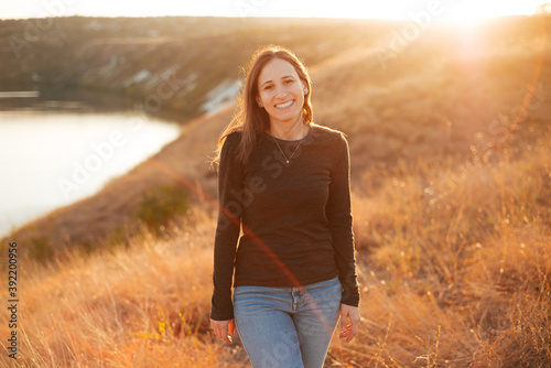 Portrait of a young woman smiling on a sunny day on field . © Vulp