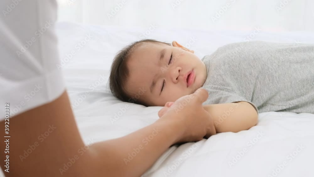 Little baby girl sleeping on bed and young mother touch hand and pat her girl's head with tenderness and care,slow motion shot. Little baby girl sleeping on bed and young mother touch hand and pat her girl's head with tenderness and care,slow motion shot.