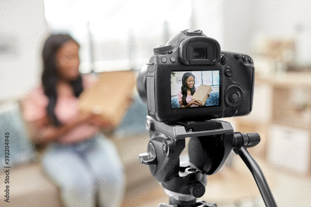 blogging, videoblog and people concept - happy smiling african american female video blogger with parcel box and camera videoblogging at home