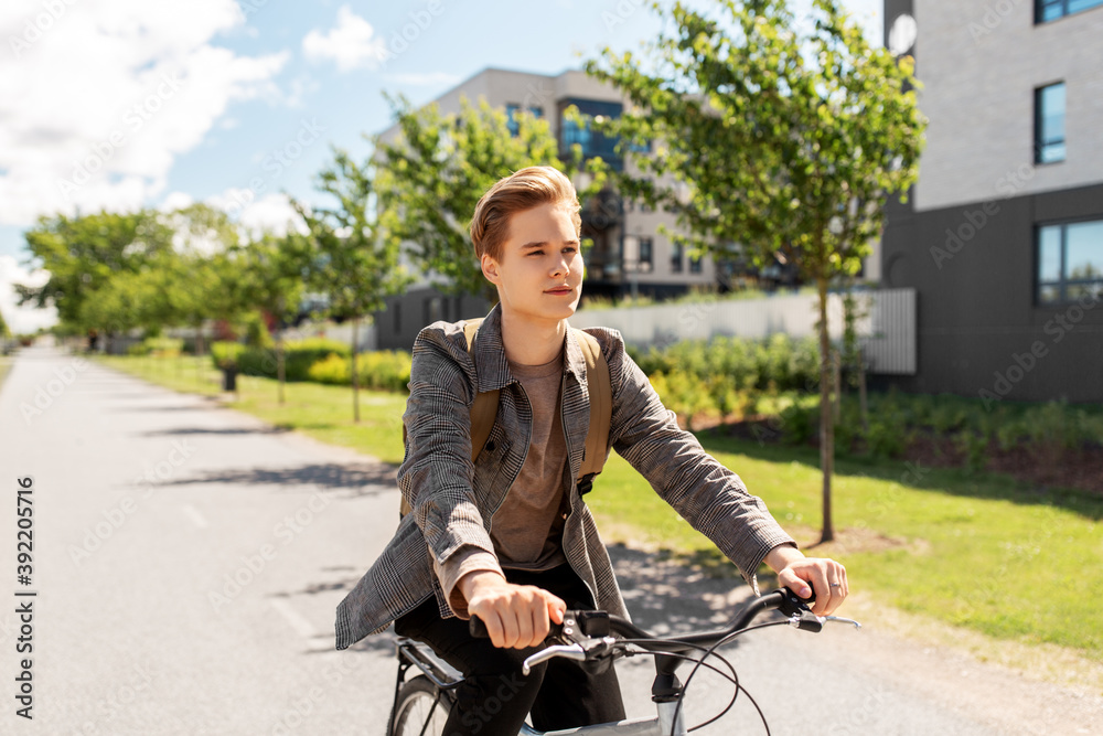 lifestyle, transport and people concept - young man or teenage student boy with backpack riding bicycle on city street