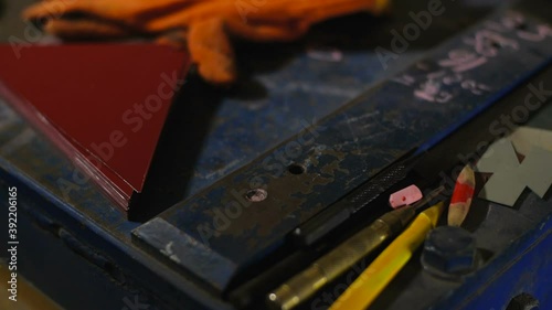 Tracking shot  of engineering tools on metal table. Protective gloves, measuring tape, pencil, metal scissors and pieces of sheet metal. Work in the workshop for the manufacture of tin products photo