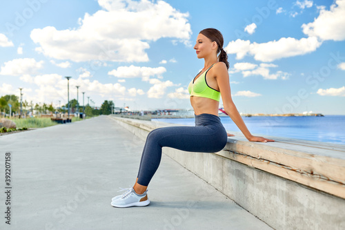 fitness, sport and healthy lifestyle concept - young woman exercising on sea promenade