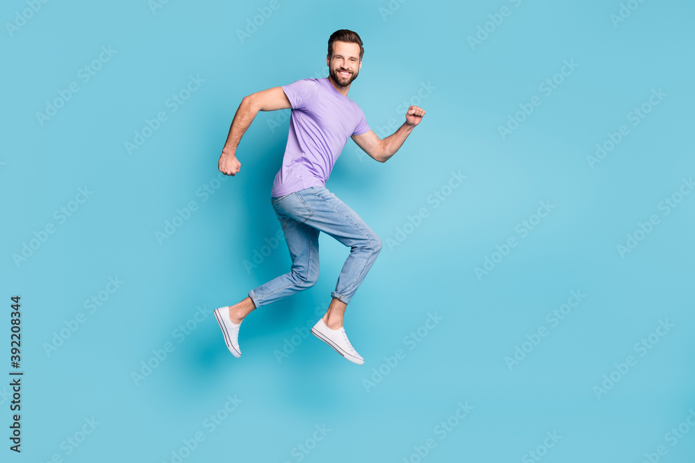 Full length body size side profile photo of young bearded student jumping high running isolated on vibrant blue color background