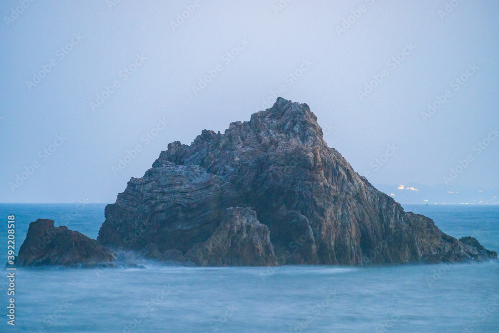 Naklejka premium 海岸の大きい岩と夕日