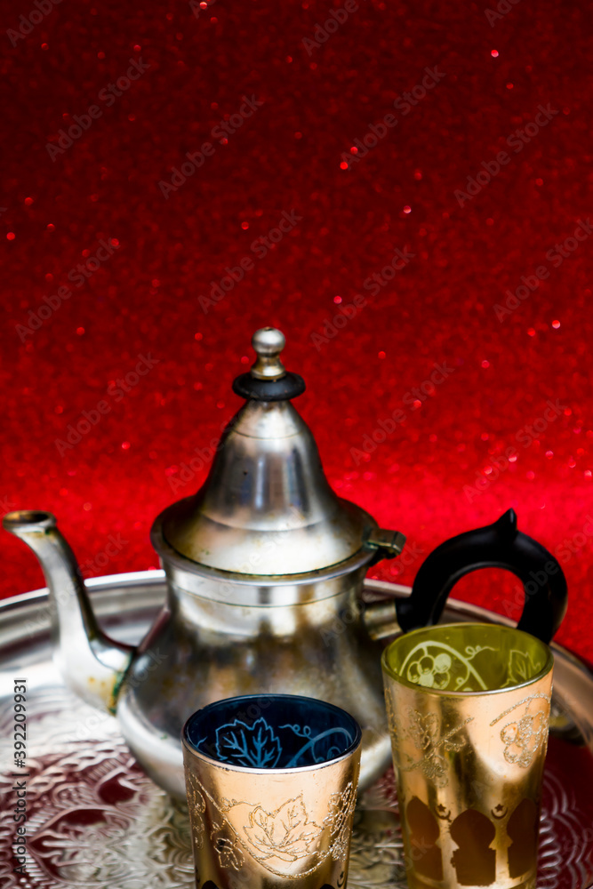Teapot and glasses of oriental tea on a tray on red background with glitter