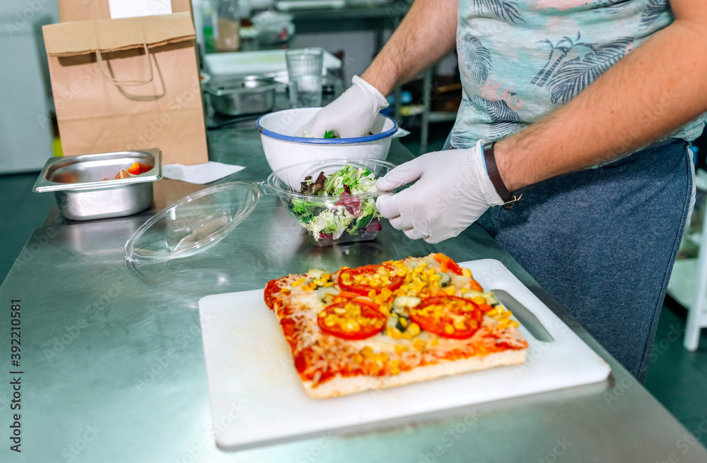 Unrecognizable cook in restaurant kitchen preparing takeaway orders