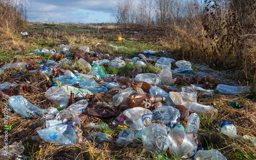 Dump of plastic bottles in autumn field on outskirts of town
