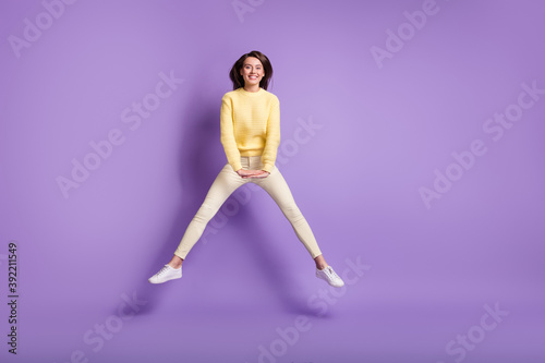 Photo portrait full body view of girl jumping up with spread legs hands down isolated on bright purple colored background
