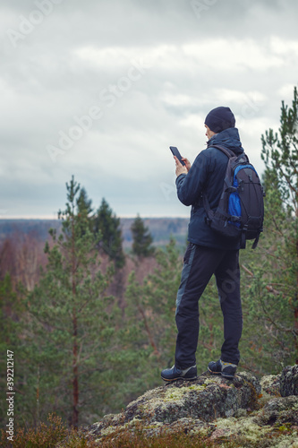Tourist man outdoors looking information in smartphone. Forest background blurred.