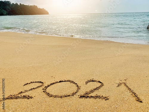 Welcome new year 2021 Write on the sand by the sea, near the sunset.