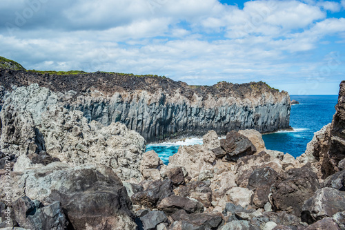 Rugged cliff with turquoise sea and bursting Atlantic Ocean wave and volcanic rocks in the foreground in Alagoa da Fajãzinha, Terceira - Azores PORTUGAL photo