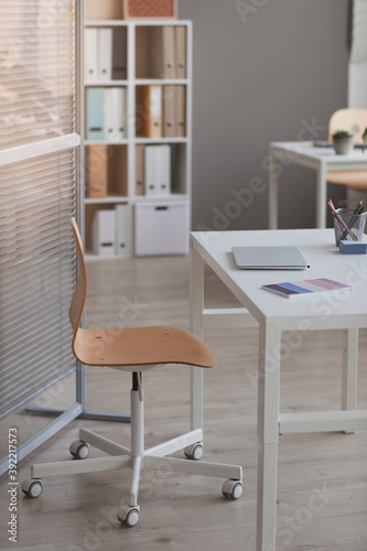 Image of empty table with laptop on it and chair at modern office © AnnaStills