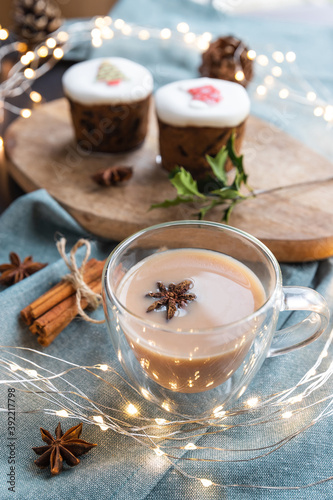 masala tea and sweet cakes on a table with Christmas decoration. Masala chai is an Indian tea beverage made by boiling black tea in milk and water with a mixture of aromatic herbs and spices
