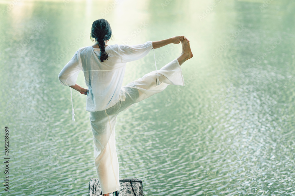Woman Practicing Yoga near Water in the Nature