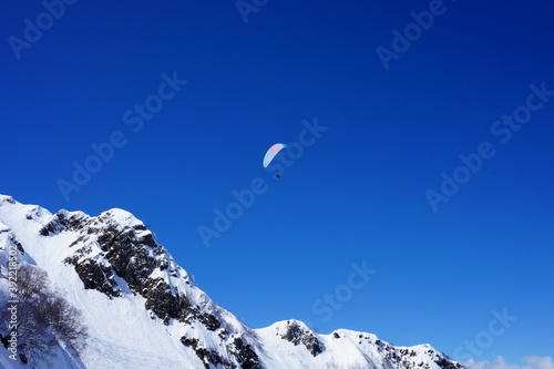 Winter landscape in the mountains. Snow-capped mountain peaks, blue sky, ski slopes.