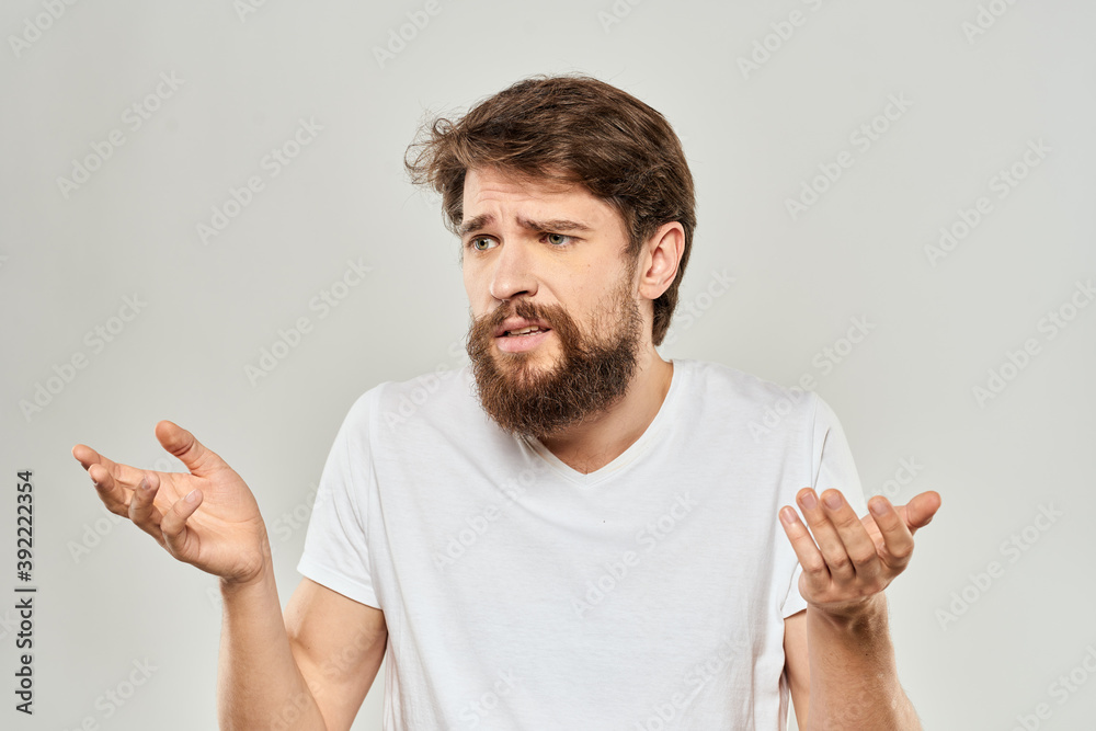man in white t-shirt gesturing with his hands studio dissatisfaction lifestyle light background man in white t-shirt gesturing with his hands studio dissatisfaction lifestyle light background