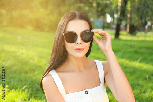 Beautiful young woman wearing stylish sunglasses in park