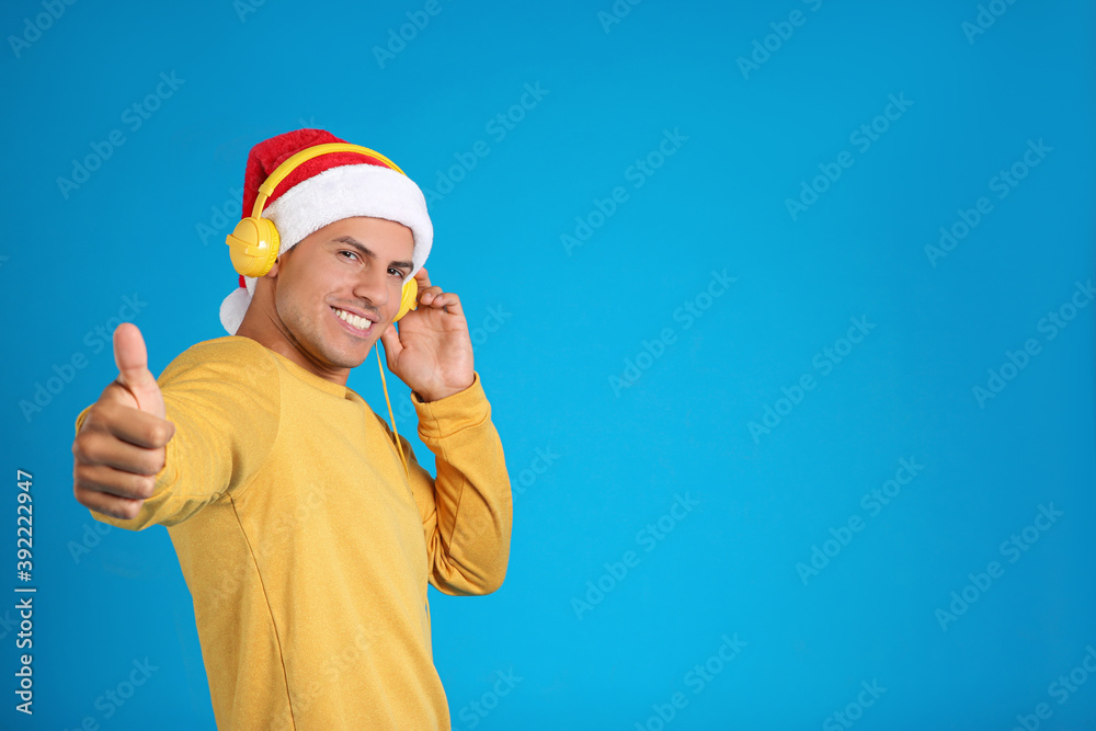 Happy man with headphones on blue background, space for text. Christmas music Happy man with headphones on blue background, space for text. Christmas music