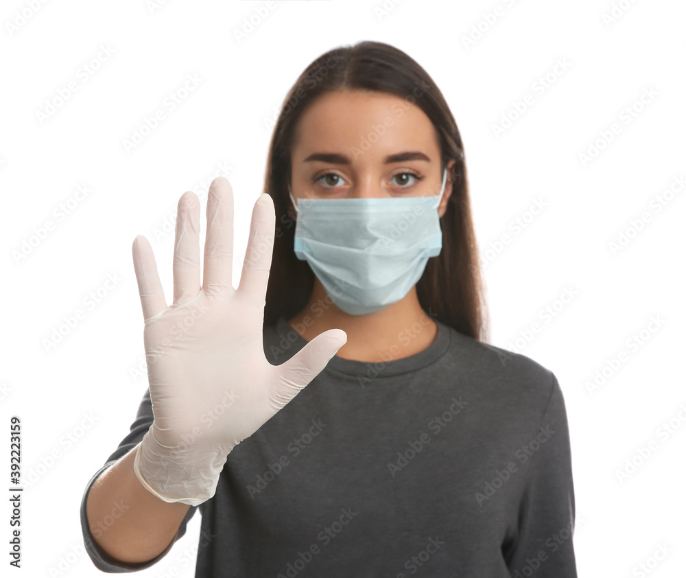Woman in protective face mask and medical gloves showing stop gesture against white background, focus on hand Woman in protective face mask and medical gloves showing stop gesture against white background, focus on hand