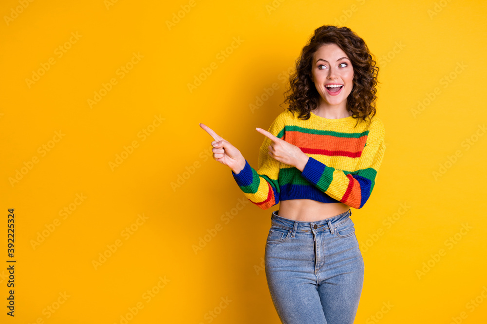 Photo portrait of laughing girl pointing two fingers at blank space isolated on vivid yellow colored background Photo portrait of laughing girl pointing two fingers at blank space isolated on vivid yellow colored background