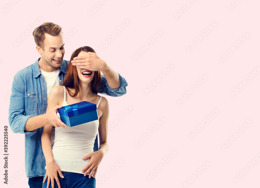 Naklejka premium Happy couple with gift box, close to each other, with copy space for text, isolated over pink background. Love, relationship, dating, flirting, lovers, romantic studio concept.