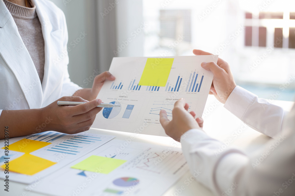 The top executive was holding a pen with his finger and pointing at the laptop explaining the company's goals to a personal secretary. The top executive was holding a pen with his finger and pointing at the laptop explaining the company's goals to a personal secretary.