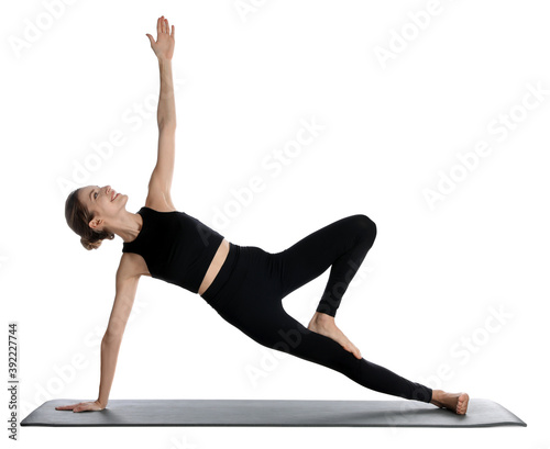 Young woman in sportswear practicing yoga on white background