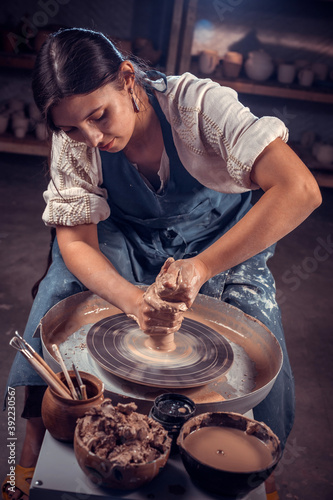 Stylish professional potter sculptor works with clay on a Potter's wheel and at the table with the tools. Hand work. photo