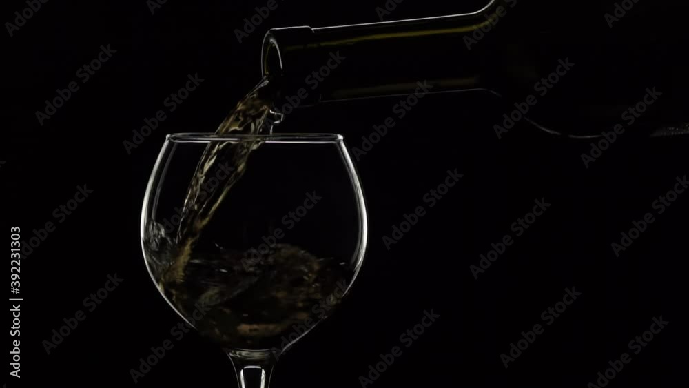 White wine pouring into glass from bottle close up. Slow motion isolated background White wine pouring into glass from bottle close up. Slow motion isolated background