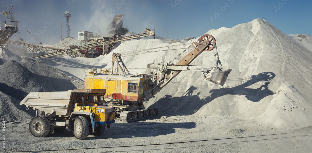 Φωτογραφία Mining excavator and mining dump truck on the background of the stone-crushing equipment of the mining enterprise, panorama
