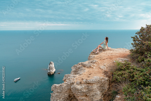 Young woman on the edge of a cliff. Portrait of a blonde, admiring the water surface. © Haibullaev