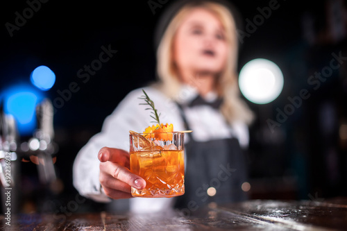 Experienced woman bartender surprises with its skill bar visitors while standing near the bar counter in pub photo