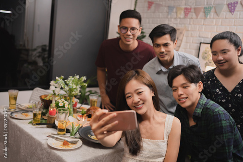 Group of Asian friends taking a selfie while having dinner after work.