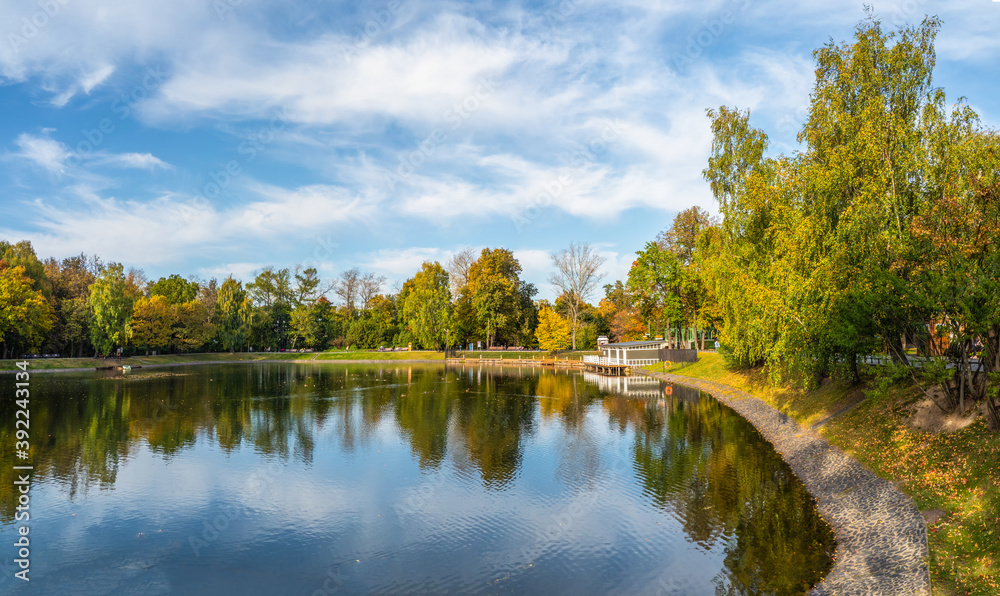 Beautiful Ostankino Park in Moscow, autumn pond with pier and reflection in the water.
