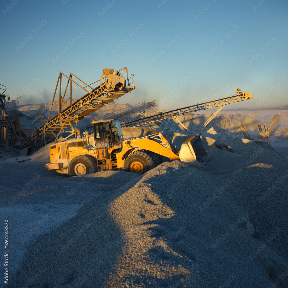 Front end loader near the stone crushing equipment at the limestone quarry. Mining industry.
