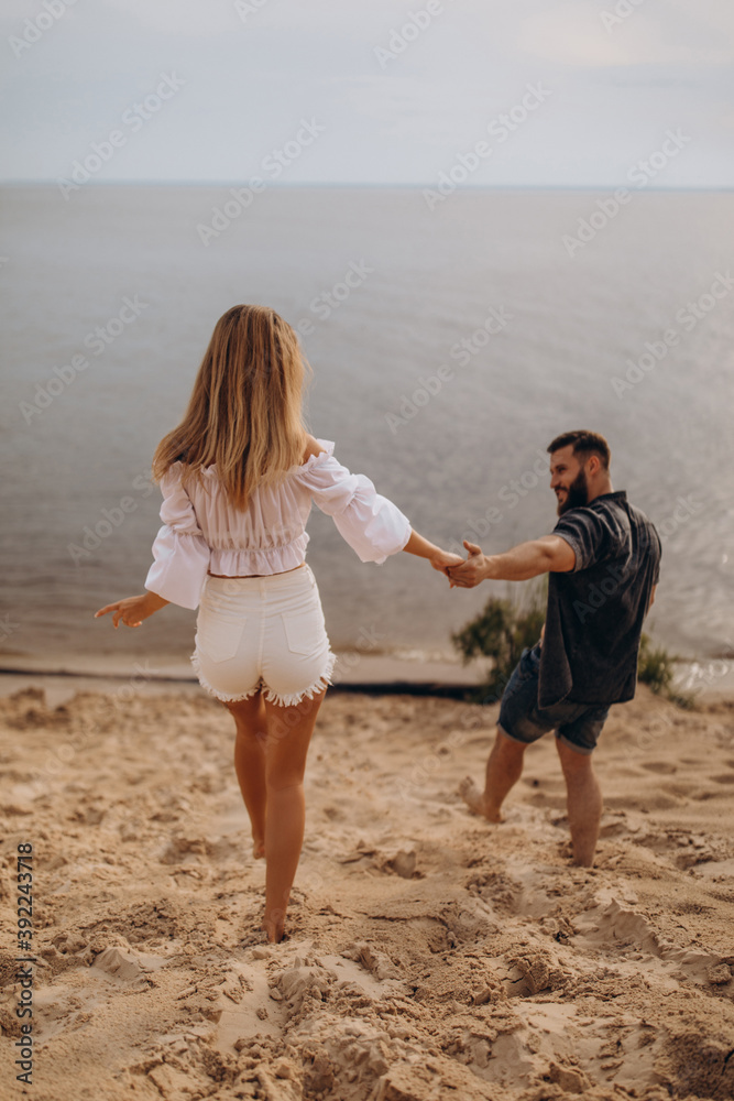 Romantic photo session of a young couple by the lake. Boy and girl summer walk.