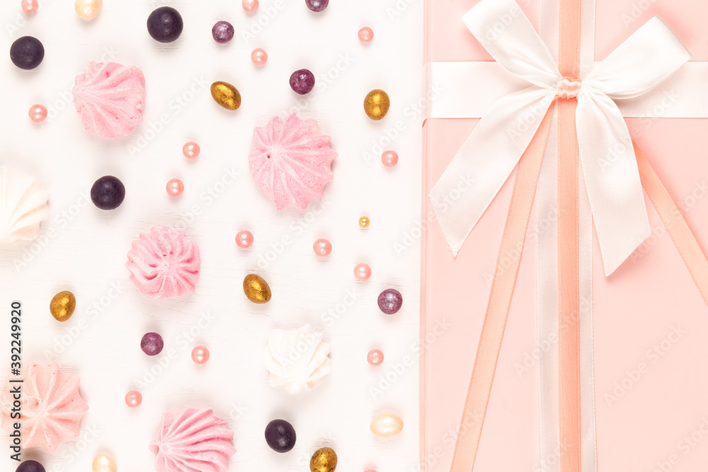 pink gift box with scattered multicolored sweets and bizet cake on a white wooden table pink gift box with scattered multicolored sweets and bizet cake on a white wooden table